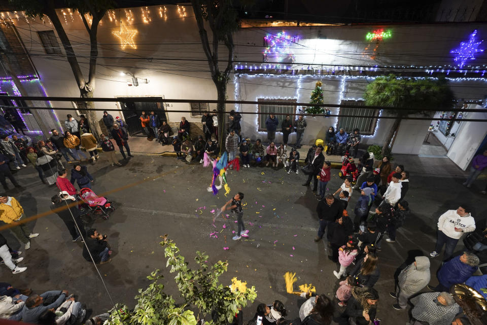 A child swings at a piñata during a street "posada" organized by neighbors in Mexico City, late Friday, Dec. 22, 2023. Posadas are nine traditional gatherings held in December until Christmas Eve that represent stops made during the pilgrimage of Saint Joseph and the Virgin Mary while looking for a place to stay and give birth to baby Jesus. (AP Photo/Marco Ugarte)