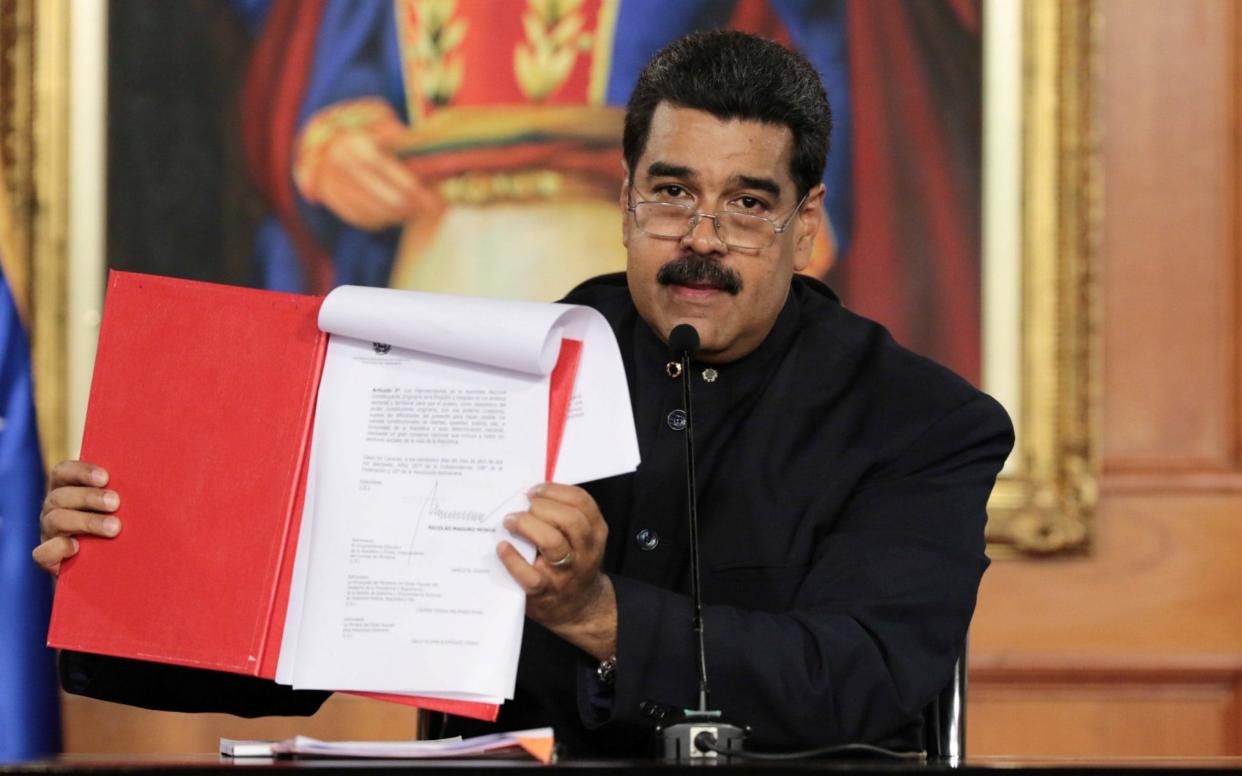 Nicolas Maduro holds a document as he speaks during a ceremony at Miraflores Palace in Caracas - REUTERS