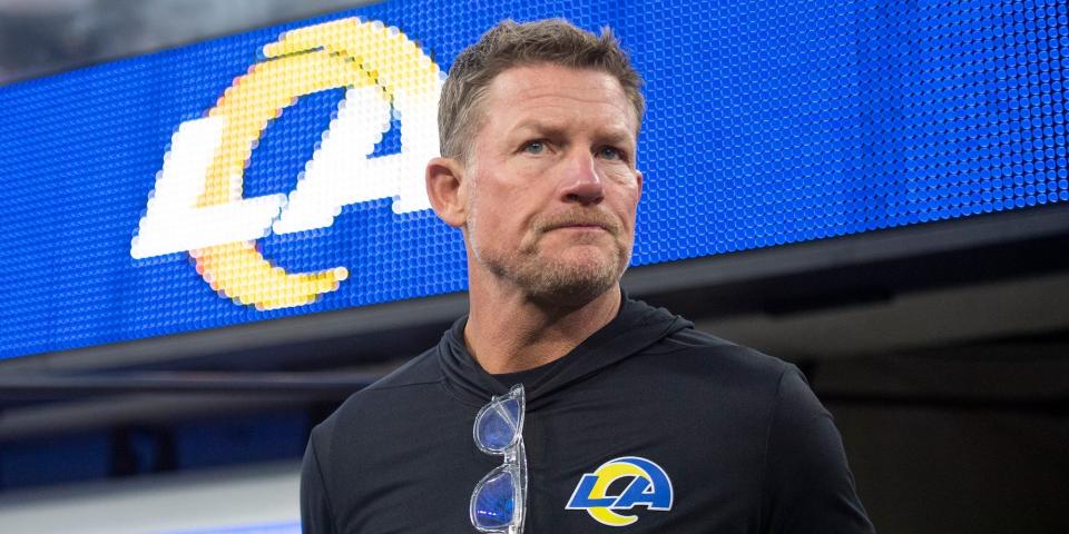 Les Snead looks on while standing in front of a Rams logo.