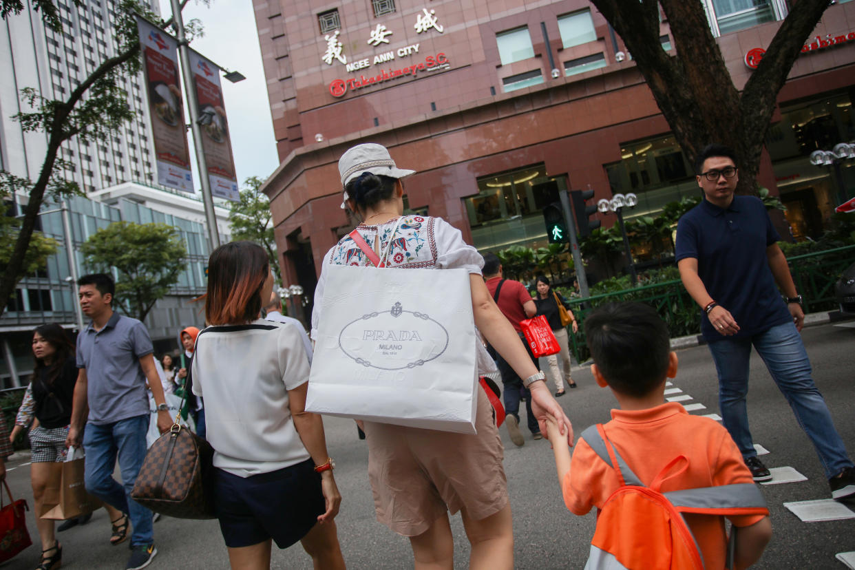 A pedestrian carrying a shopping bag crossing a junction at Orchard Road. (FILE PHOTO: Yahoo News Singapore)