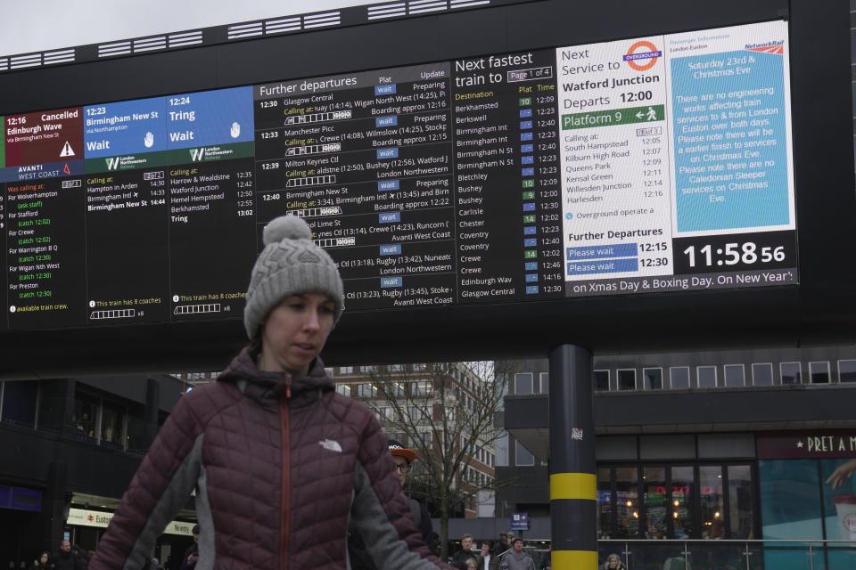 A traveller stands in front of an information display giving travel details for the upcoming Christmas holiday period at Euston Station in London, Thursday, Dec. 21, 2023. London Rail travellers over the Christmas holiday season will have to contend with disruptions to services due to engineering work and bad weather. (AP Photo/Kin Cheung)