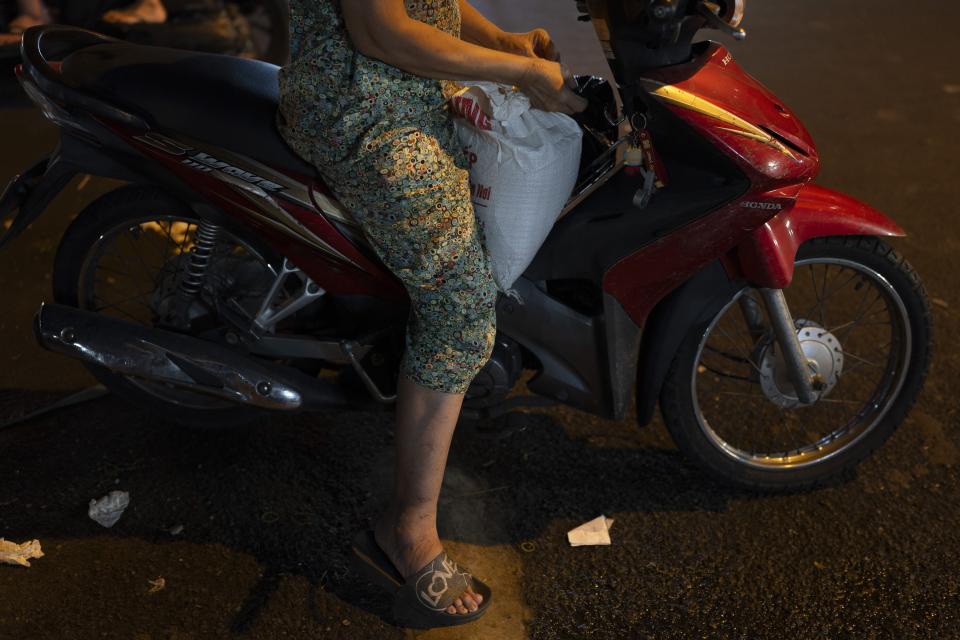 A woman sits on a scooter with a bag of rice purchased from a local market in Ho Chi Minh City, Vietnam, Wednesday, Jan. 24, 2024. Vietnam is the world's third largest rice exporter, and the staple importance to Vietnamese culture is palpable in the Mekong Delta. (AP Photo/Jae C. Hong)