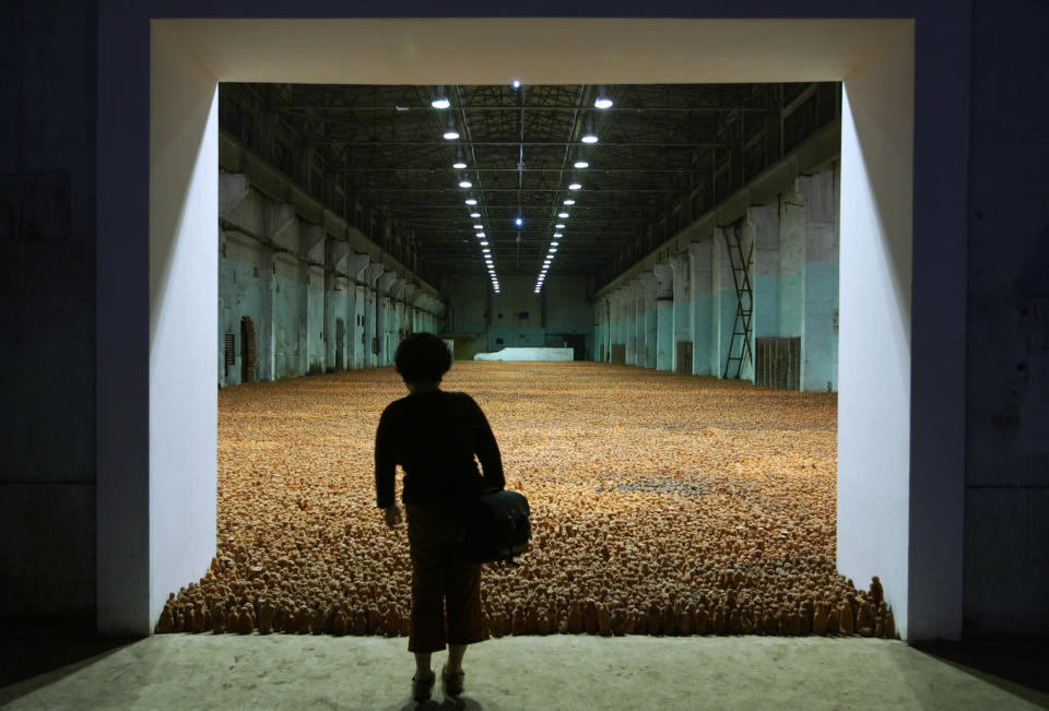 Un visitante observa una gigante escultura exhibida en una bodega, por el artista británico Antony Gormley, titulada "Asian Field" en Shanghai, en octubre de 2003. La pieza se compone de 192 fiugras de arcilla. REUTERS/Claro Cortes IV