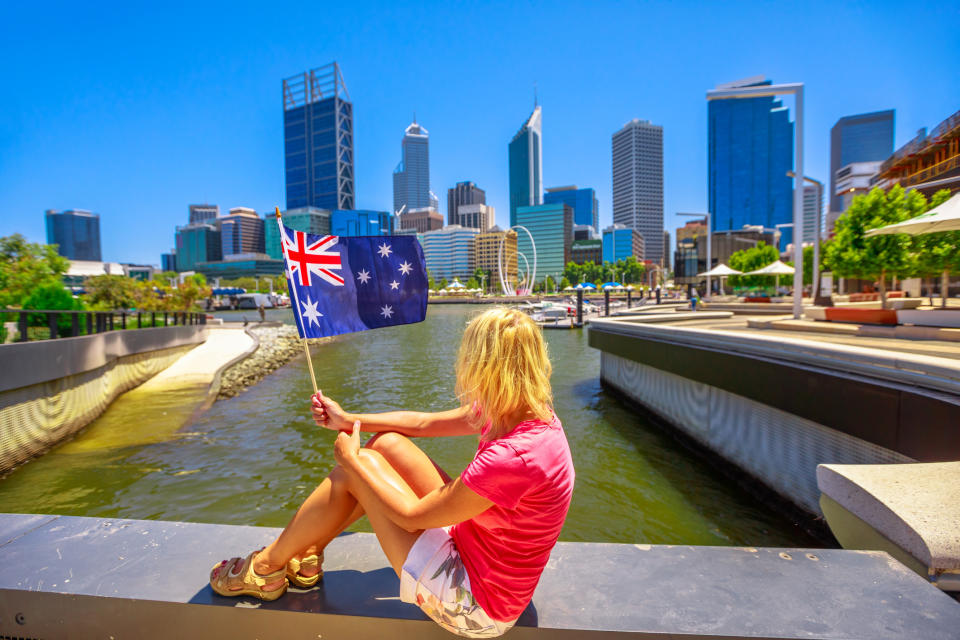 Blonde woman with Australian flag on Elizabeth Quay Marina promenade in a sunny day