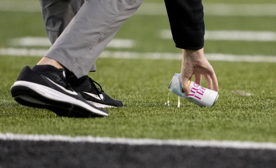 An Iowa staff member removes a beverage can that was thrown by a fan onto the field during the second half of an NCAA college football game against Minnesota, Saturday, Oct. 21, 2023, in Iowa City, Iowa, (AP Photo/Matthew Putney)