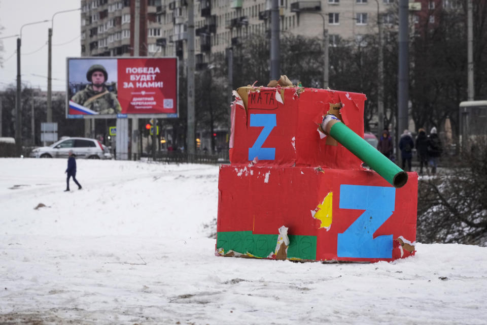 FILE - A man walks past a billboard with a portrait of a Russian soldier, a participant of the action in Ukraine and the words 'The victory will be ours!' and a tank mockup made from boxes, in St. Petersburg, Russia, Feb. 18, 2023. U.S. officals say Russia is now the most sanctioned country in the world. But as the war nears its one-year mark, it's clear the sanctions didn't pack the instantaneous punch that many had hoped. (AP Photo/Dmitri Lovetsky, File)