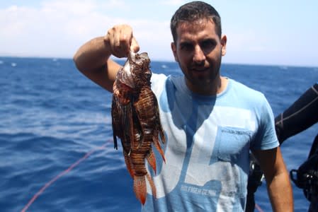 Periklis Kleitou, a marine scientist, holds a lionfish after a dive at the Zenobia, a cargo ship wreck off Larnaca