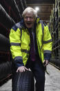 Britain's Prime Minister Boris Johnson wheels a tire, during a General Election campaign visit to Ferguson's Transport in Washington, west of Sunderland, northeast England, Monday, Dec. 9, 2019. Britain goes to the polls on Dec. 12. (Ben Stansall/Pool Photo via AP)