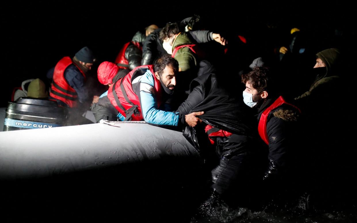 Migrants get on an inflatable dinghy as they leave the coast of northern France to cross the English Channel - Reuters