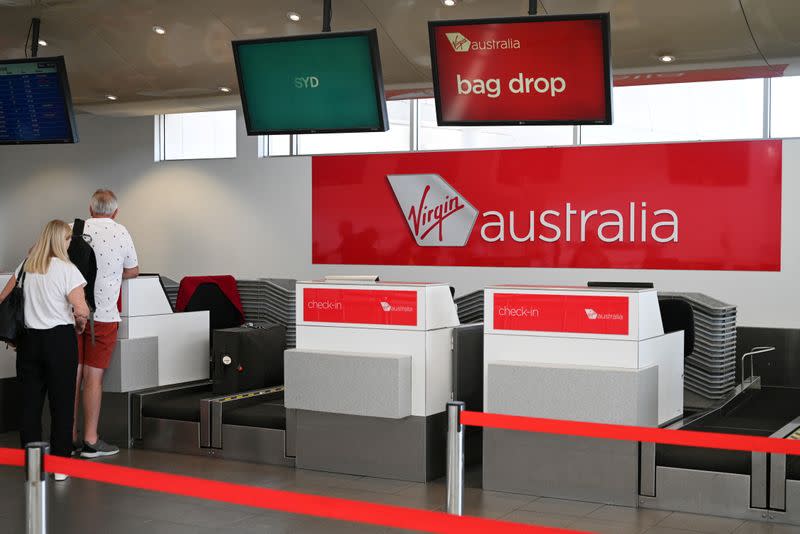 FILE PHOTO: Travelers stand at a Virgin Australia Airlines counter at Kingsford Smith International Airport in Sydney