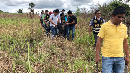 Police officers carry the body of Sebastian Woodroffe, a 41-year-old Canadian citizen, who was beaten and strangled with a rope in the jungle region of Ucayali on Friday after members of an indigenous community accused him of killing a revered medicine woman, in Pucallpa, Peru April 21, 2018. REUTERS/ Hugo Enrique Alejos