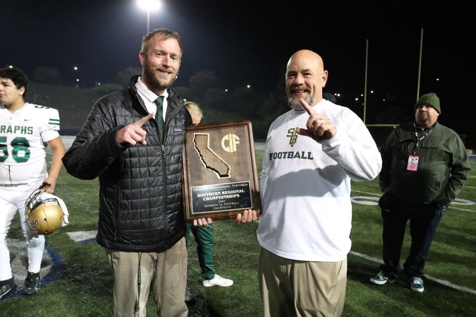 St. Bonaventure head coach Joey Goyeneche and defensive coordinator Nate Page hold the championship plaque after the Seraphs rallied to defeat St. Augustine 21-20 in the CIF-State Division 1-A regional final last Saturday.