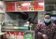 Stores owners of a store selling a local favorite "reganmian," or "hot dry noodles," prepare takeaway orders in Wuhan in central China's Hubei province, Tuesday, March 31, 2020. The reappearance of Wuhan's favorite noodles is a tasty sign that life is slowly returning to normal in the Chinese city at the epicenter of the global coronavirus outbreak. The steady stream of customers buying bags of noodles smothered in peanut sauce testifies to a powerful desire to enjoy the familiar again after months of strict lockdown. (AP Photo/Olivia Zhang)