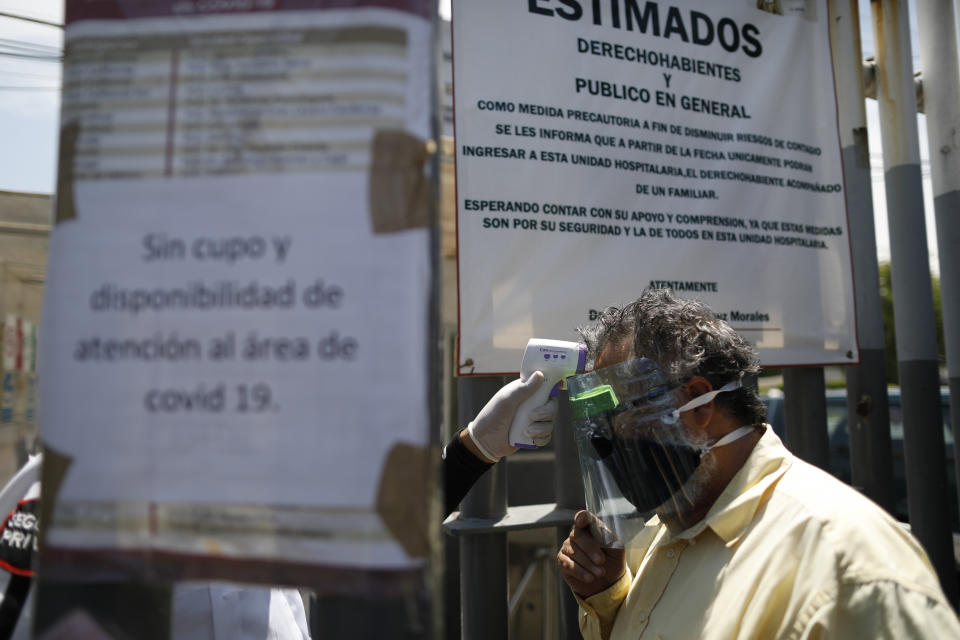 A man has his temperature taken by infrared thermometer as he enters the grounds of a government hospital, marked with signs announcing that the COVID-19 ward is full, in the Iztapalapa district of Mexico City, Tuesday, May 5, 2020. Mexico's densely populated capital is one of the hardest hit areas of the country, with thousands of confirmed cases, as well as many more suspected, and around 500 deaths.(AP Photo/Rebecca Blackwell)