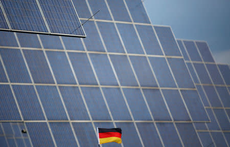 A German national flag is pictured in front of solar panels in Bad Hersfeld May 14, 2013. REUTERS/Lisi Niesner/Files