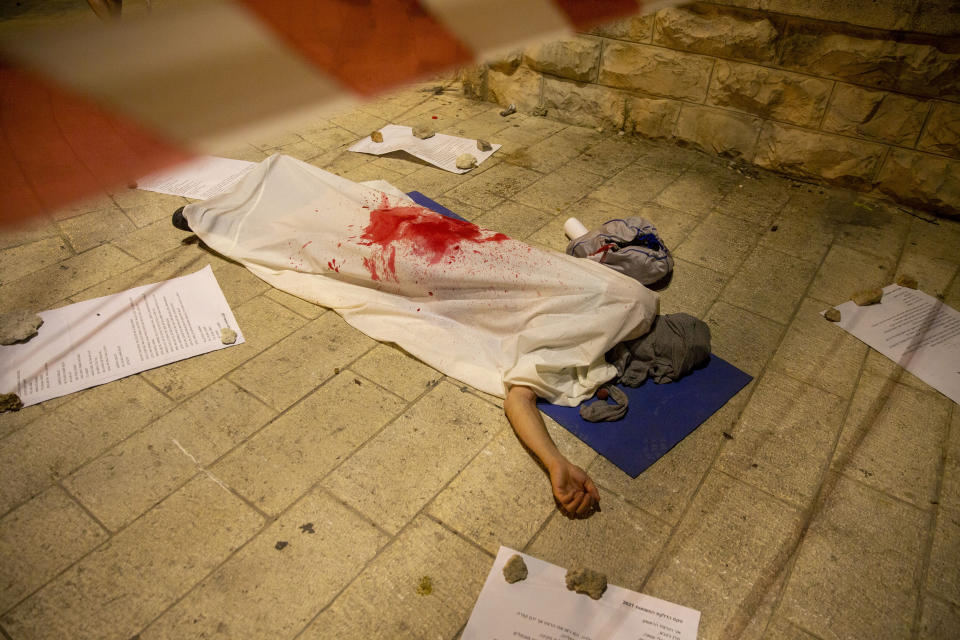 A protester acts as a dead body to symbolize political murder, during a protest against Israeli Prime Minister Benjamin Netanyahu in Jerusalem, Thursday, July 30, 2020. (AP Photo/Ariel Schalit)