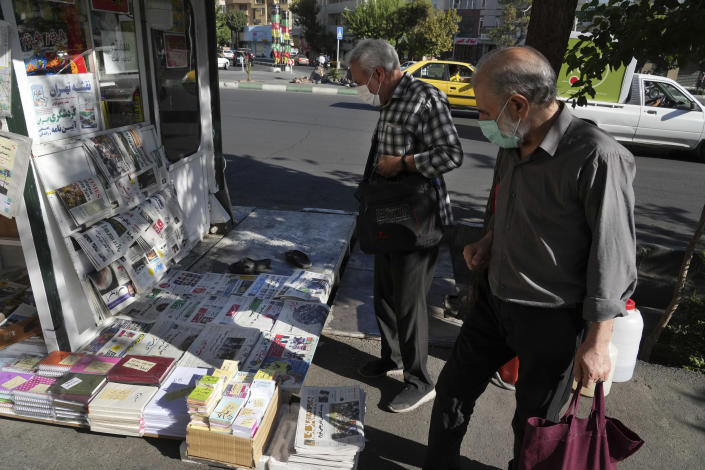 People scan publications at a news stand in Tehran, Iran, Saturday, Aug. 13, 2022. Salman Rushdie, whose novel “The Satanic Verses” drew death threats from Iran’s leader in the 1980s, was stabbed in the neck and abdomen Friday by a man who rushed the stage as the author was about to give a lecture in western New York. (AP Photo/Vahid Salemi)