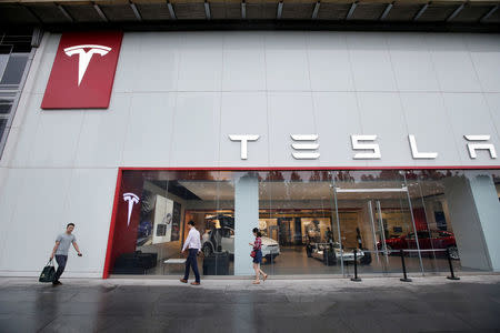 FILE PHOTO: People walk past a showroom outside Tesla China headquarters at China Central Mall in Beijing, China July 11, 2018. REUTERS/Jason Lee/File Photo