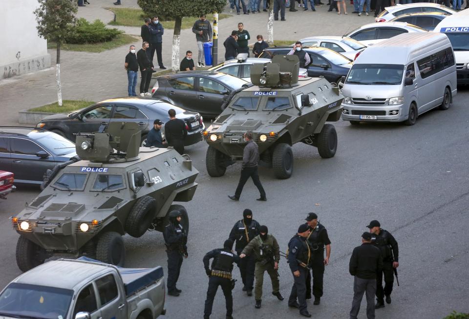 Georgian police gather at a bank where an armed assailant took several people hostage in the town of Zugdidi in western Georgia, Wednesday, Oct. 21, 2020. An armed assailant took several people hostage at a bank in the ex-Soviet nation of Georgia on Wednesday, authorities said. The Georgian Interior Ministry didn't immediately say how many people have been taken hostage in the town of Zugdidi in western Georgia, or what demands the assailant has made. Police sealed off the area and launched an operation "to neutralize the assailant," the ministry said in a statement. (AP Photo/Zurab Tsertsvadze)