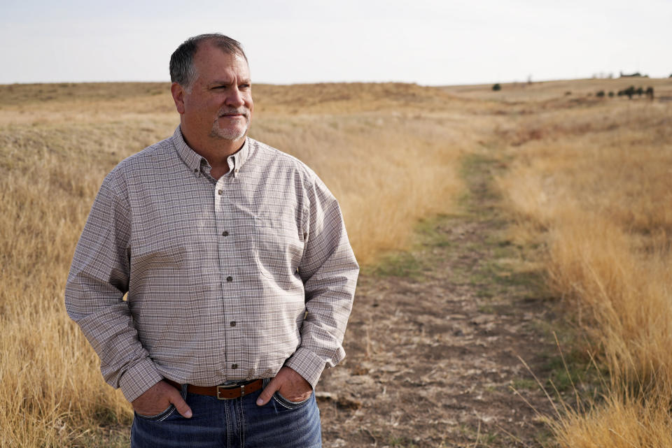 Jay Goddard, a regional president of a bank, stands in the path of the old canal attempt that cuts through his property Thursday, April 28, 2022, in Julesburg, Colo. His bank provides operating loans to farmers on both sides of the border to keep them running until harvest time. (AP Photo/Brittany Peterson)