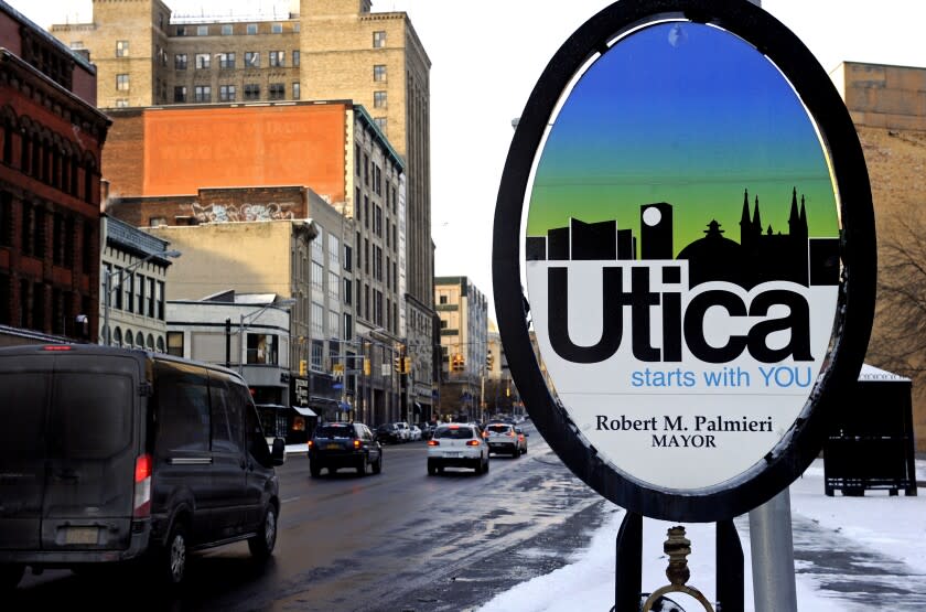 Vehicles move along Genesee Street in the early morning after a fresh snowfall, in Utica, N.Y.