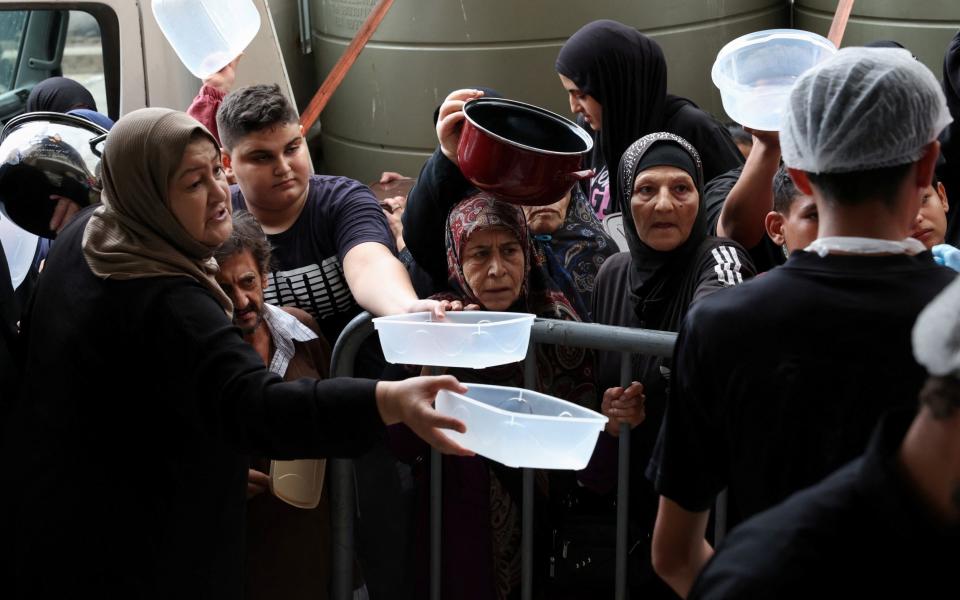 Displaced people queue for food cooked by a charity kitchen in downtown Beirut on Thursday.