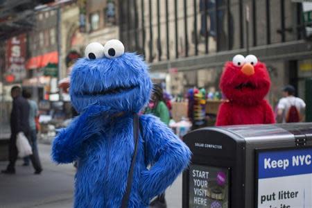 Characters dressed up as the Cookie Monster and Elmo from Sesame Street stand in Times Square while waiting to pose for photographs with people for tips in New York April 9, 2013. REUTERS/Shannon Stapleton