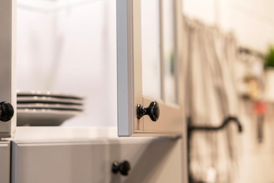 Open cabinet door on a kitchen cabinet with dishes inside cabinet.