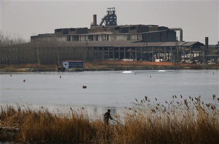 A man attempts to catch fish at a partially frozen fish farm near an abandoned steel mill of Qingquan Steel Group in Qianying township, Hebei province February 18, 2014. REUTERS/Petar Kujundzic