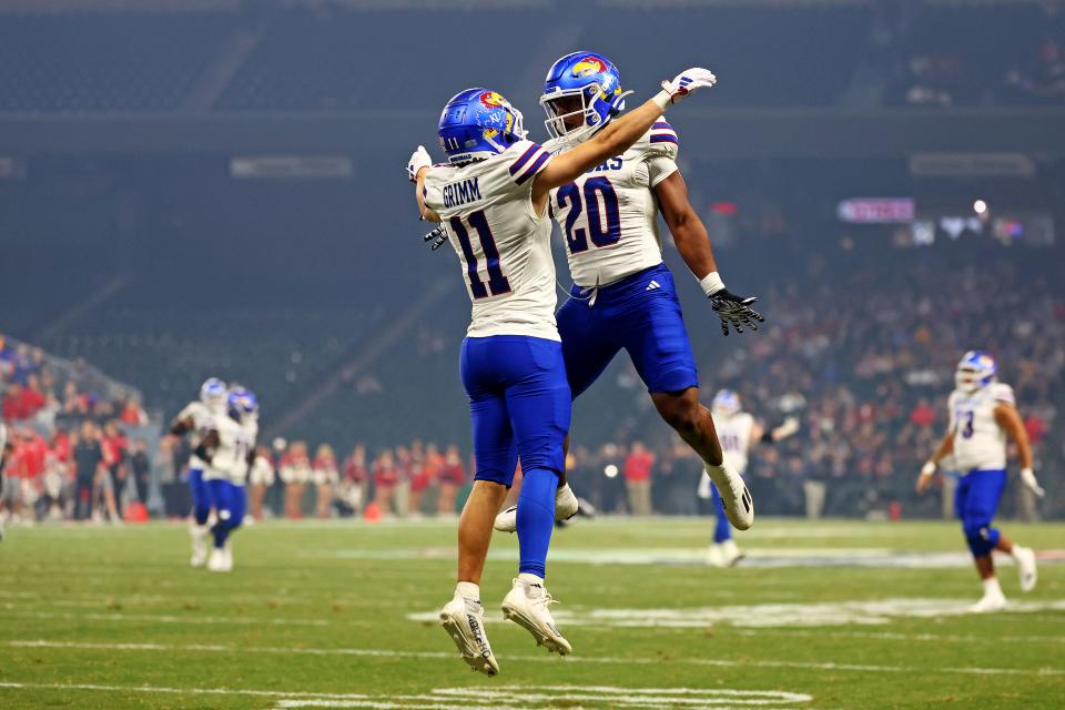 Kansas football wide receiver Luke Grimm (11) celebrates with running back Daniel Hishaw Jr. (20) after scoring a touchdown during the second quarter of a Dec. 26, 2023 game against UNLV in the Guaranteed Rate Bowl at Chase Field in Phoenix.