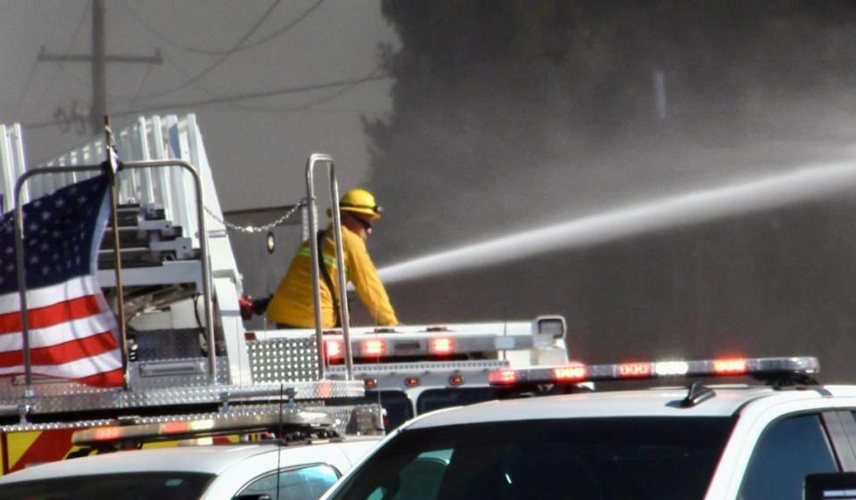 Firefighter sprays water onto pallets after a fire started in the back of a business in Fresno, California on Saturday, May 25. 2024.