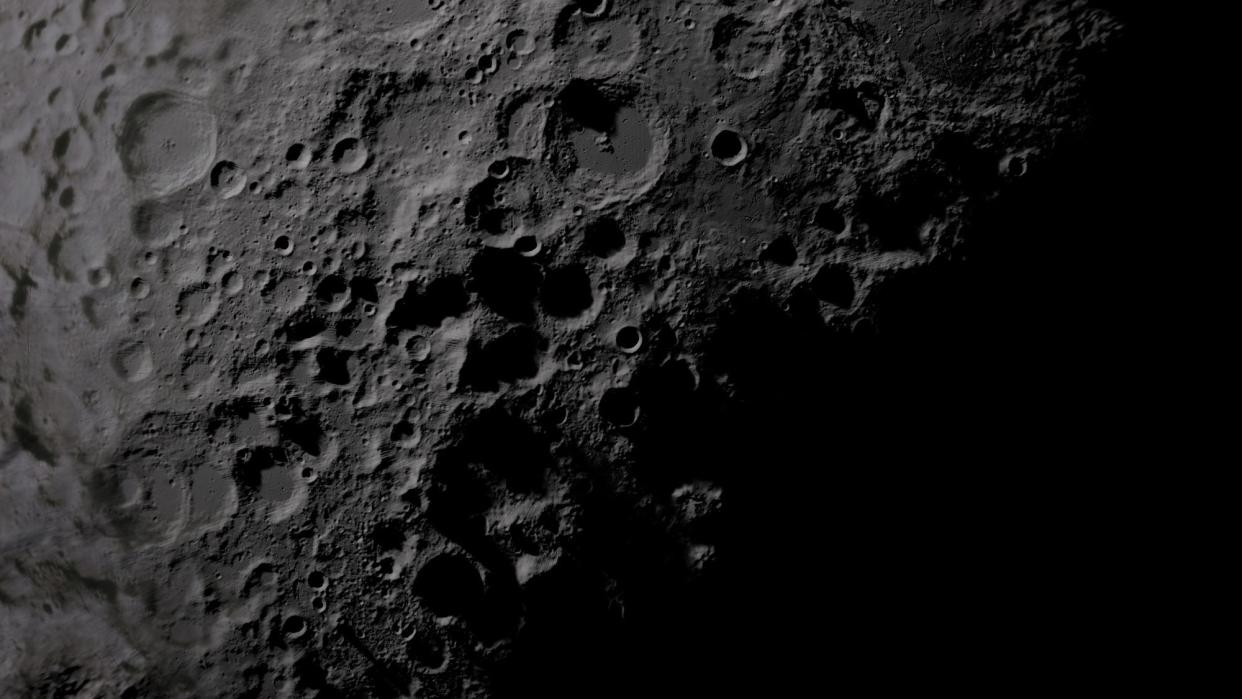 Pale craters on the moon's lunar surface, with dark shadows below.