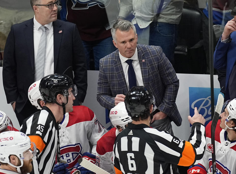 Montreal Canadiens coach Martin St. Louis, back, argues with referees Cody Beach, left front, and Francis Charron during the first period of the team's NHL hockey game against the Colorado Avalanche on Tuesday, March 26, 2024, in Denver. (AP Photo/David Zalubowski)
