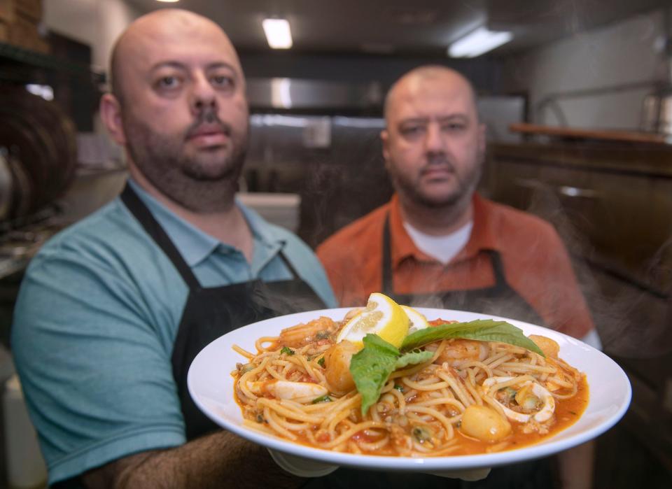 Pizzaioli Co-owner Fred Peter shows off his Fruit De Mari while his brother and Co-owner Joseph Peter watches on Monday, March 4, 2024. Fruit De Mari is a pasta dish of shrimp, calamari, baby scallops, and chopped clams cooked in our spicy marinara sauce served on top of spaghetti.
