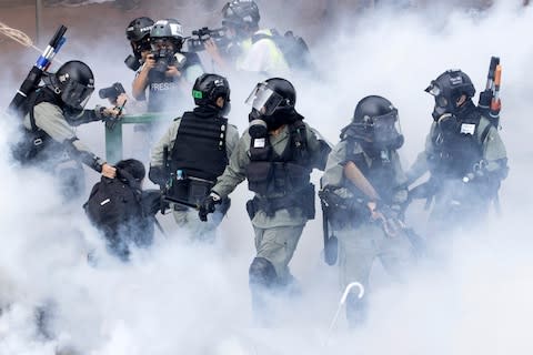 Police in riot gear move through a cloud of smoke as they detain a protester in Hong Kong - Credit: Ng Han Guan&nbsp;/AP