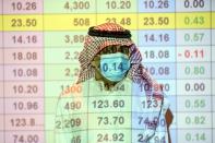 FILE PHOTO: A Saudi trader wears a mask as he monitors stock information at the Saudi stock market in Riyadh