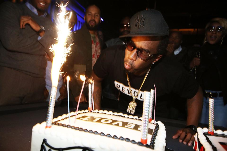 Sean Combs blowing candles out on a cake that says Revolt