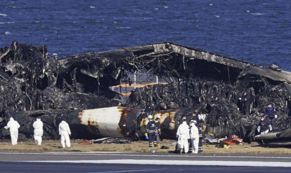 Officials investigate the wreckage of Japan Airlines plane at Haneda airport on Thursday, Jan. 4, 2024, in Tokyo, Japan. A transcript of communication between traffic control and two aircraft that collided and burst into flames at Tokyo’s Haneda Airport showed that only the larger Japan Airlines passenger flight was given permission to use the runway where a coast guard plane was preparing for takeoff. (Kyodo News via AP)