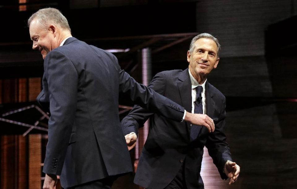 Starbucks CEO Howard Schultz, right, heads off the stage after introducing President and Chief Operating Officer Kevin Johnson at the company's annual shareholders meeting, Wednesday, March 22, 2017, in Seattle. Johnson takes over as CEO from Schultz, who will become executive chairman, in April. (AP Photo/Elaine Thompson)