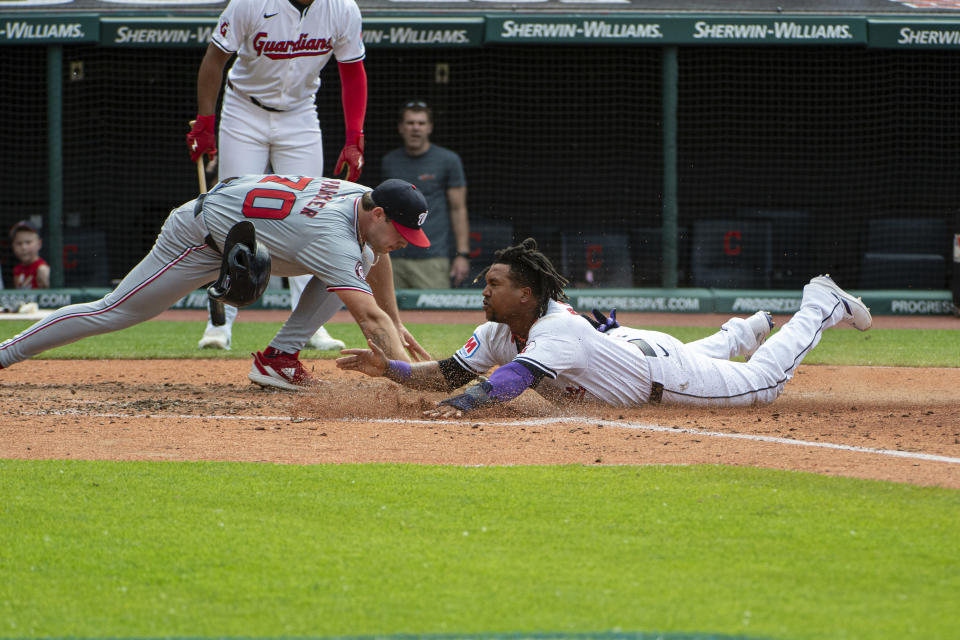 Cleveland Guardians' Jose Ramirez, right, slides safely into home plate on a passed ball as Washington Nationals starting pitcher Mitchell Parker, front left, is late with the tag during the third inning of a baseball game in Cleveland, Saturday, June 1, 2024. (AP Photo/Phil Long)