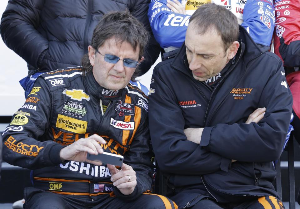 Drivers Wayne Taylor, left, and Max Angelelli, of Italy, look over a smart phone after practice for the IMSA Series Rolex 24 hour auto race at Daytona International Speedway in Daytona Beach, Fla., Friday, Jan. 24, 2014.(AP Photo/John Raoux)