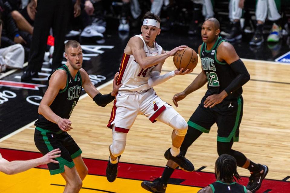 Miami Heat guard Tyler Herro (14) hangs in the air as he looks to pass while defended by Boston Celtics center Kristaps Porzingis (8) during the second half of Game three of an NBA basketball first-round playoff series at Kaseya Center in Miami, Florida, on Saturday, April 27, 2024. D.A. Varela/dvarela@miamiherald.com