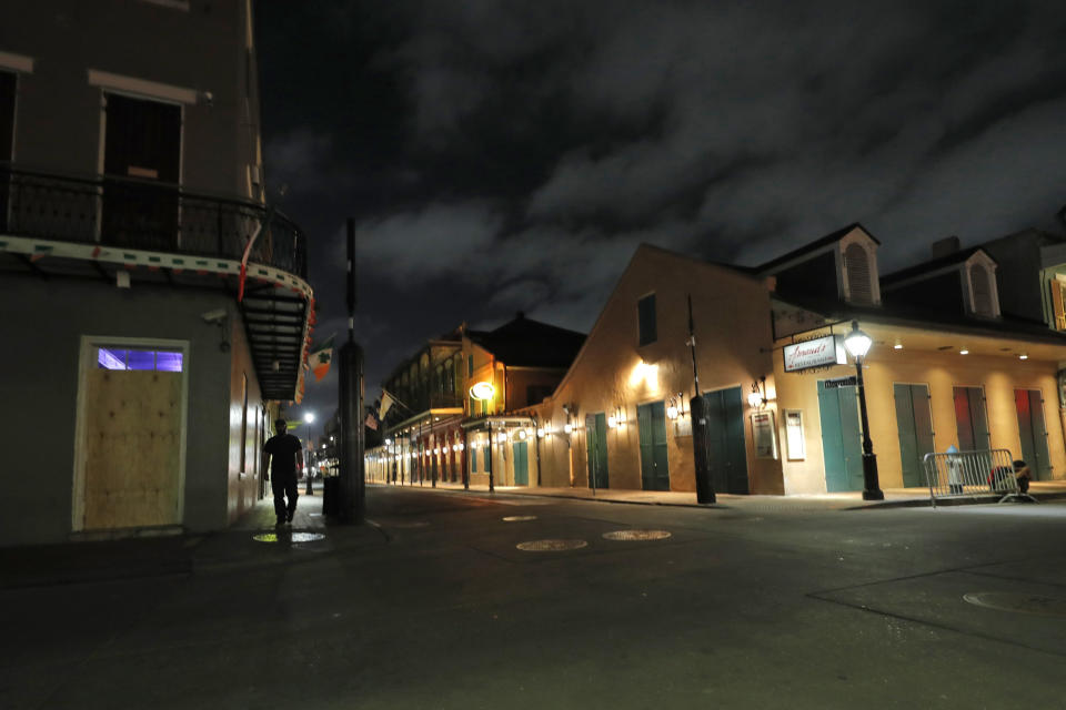 FILE - In this Thursday, March 19, 2020, file photo, a view of the nearly deserted Bourbon Street, which is normally bustling with tourists and revelers, is seen in the French Quarter of New Orleans. The old saying “Let the good times roll” has given way here to a new municipal maxim: “Wash your hands.” A month ago the city was awash in people and steeped in its annual tradition of communal joy — the Mardi Gras season. But now New Orleans has joined those places shutting down bars, eliminating restaurant dining and banning crowds. (AP Photo/Gerald Herbert, File)