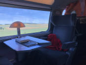 A lamp illuminates the desk of a seat on the French high speed TGV train travelling from Paris to Zurich, Saturday, May 21, 2022. The World Economic Forum is encouraging European attendees to come to its exclusive gathering in the Swiss Alps by train. Its part of efforts to burnish the sustainability credentials for an event in Davos that conjures up up images of government leaders, billionaire elites and corporate titans jetting in on carbon-spewing private planes. (AP Photo/Kelvin Chan)