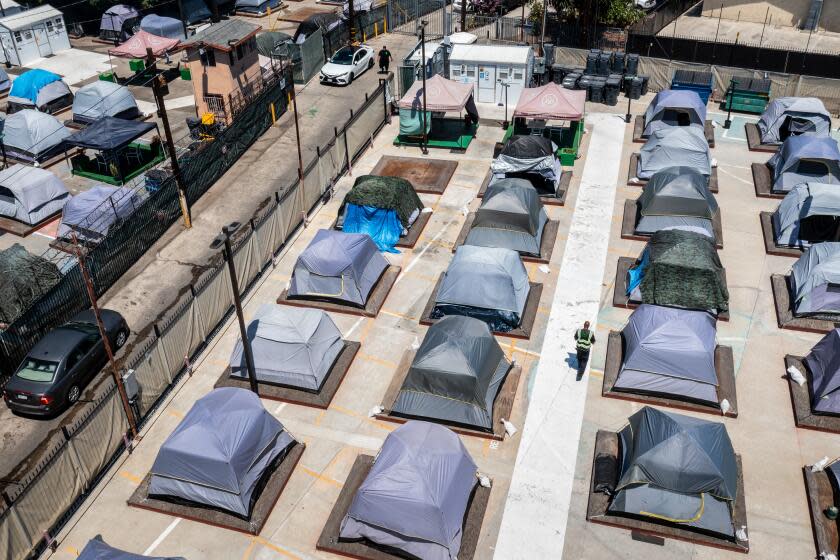 Los Angeles, CA - August 14: A drone's view of a visit to the Urban Alchemy homeless site, along South Central Avenue, in Los Angeles, CA, Monday, Aug. 14, 2023. Urban Alchemy, a San Francisco-based homeless services nonprofit, is exploring a form of homeless shelter where people live in tents for as long as they want, with no curfews and few rules and can recieve help applying for the support of a government-run program. The space has room for 90 people at capacity, housed in tents placed on palettes sitting several inches above the ground. (Jay L. Clendenin / Los Angeles Times)