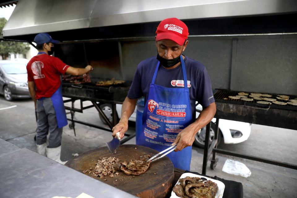 Chefs prepare meat at an outdoor area