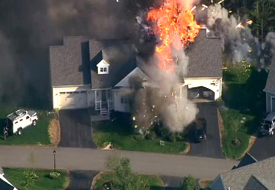 In this frame grab from television helicopter video, a police SWAT team, left, is parked on the lawn of a home in Brentwood, N.H., as it explodes in flames, Monday May 12, 2014. Shots were fired just before the fire, which involved a police officer, according to the New Hampshire State Police. (AP Photo/WCVB-TV 5) TV OUT