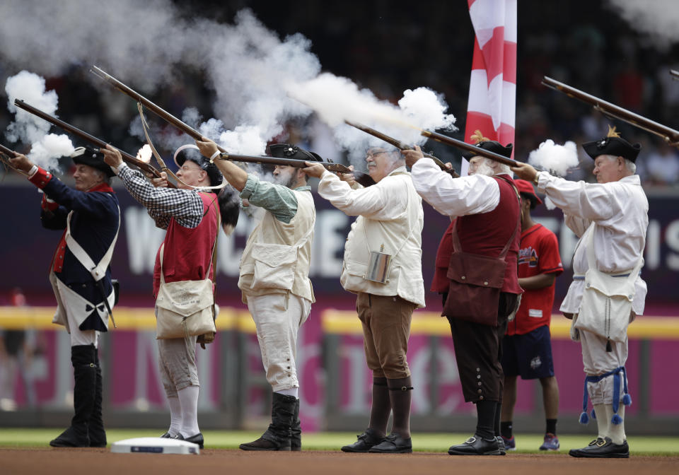 Men dressed as Revolutionary War soldiers fire a volley prior to the national anthem before the baseball game between the Atlanta Braves and Miami Marlins Sunday, July 4, 2021, in Atlanta. (AP Photo/Ben Margot)