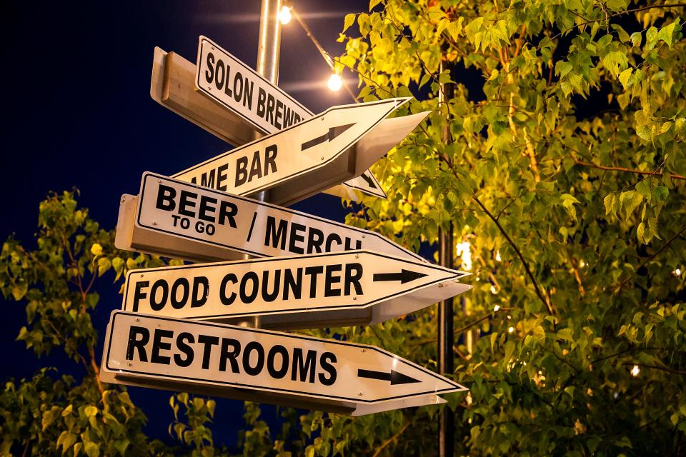 Signs hanging from an awning outside direct customers to points of interest, Tuesday, July 6, 2021, at Big Grove Brewery & Taproom in Iowa City, Iowa.
