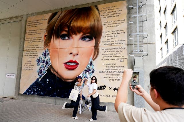 Fans pose for selfies in front of a mural of Taylor Swift outside Wembley Stadium